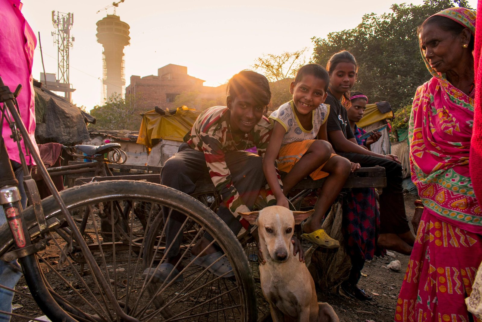 A joyful group of people with a dog on a busy Haora street at sunset, showcasing community spirit.